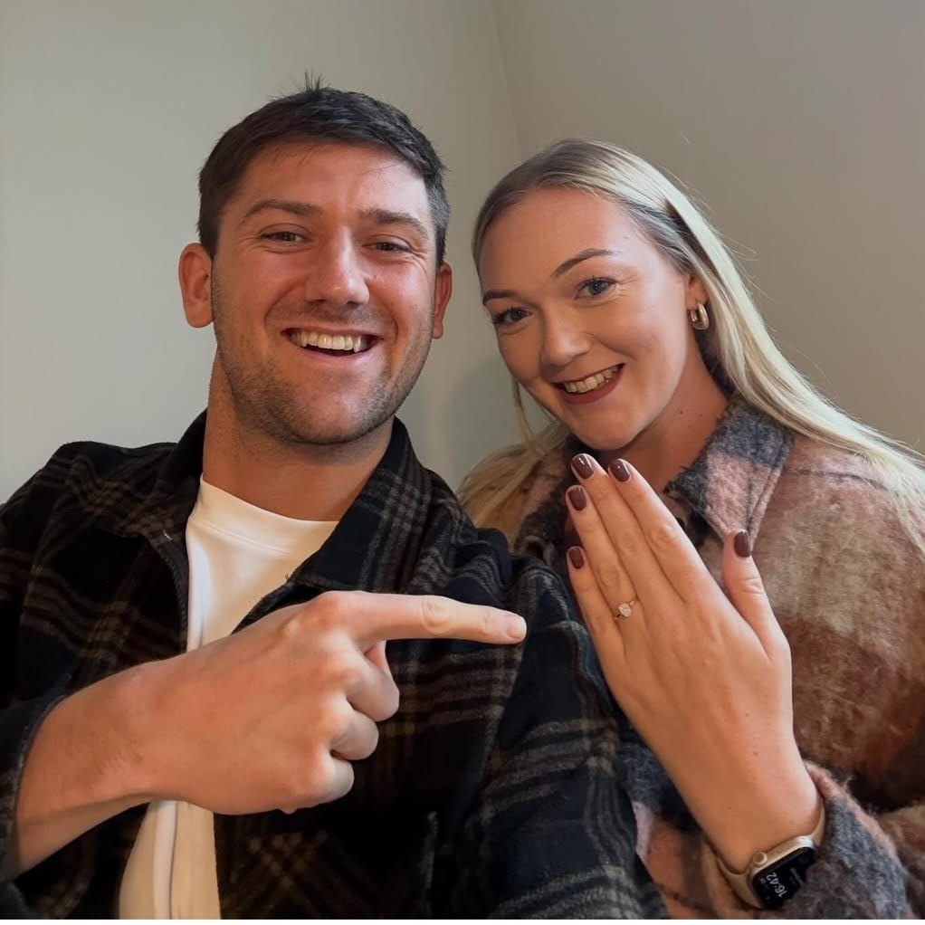 George and Alex celebrating their engagement, with Alex showing her ring