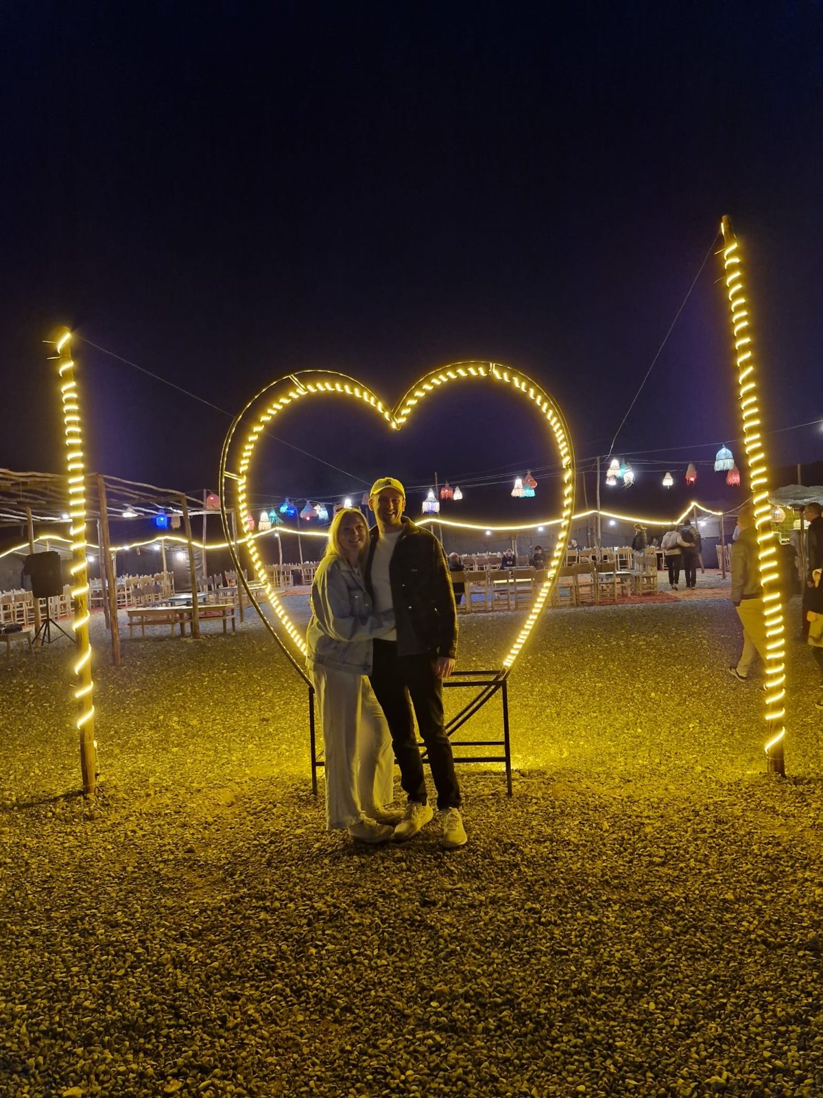 Alex and George beneath a glowing heart at night